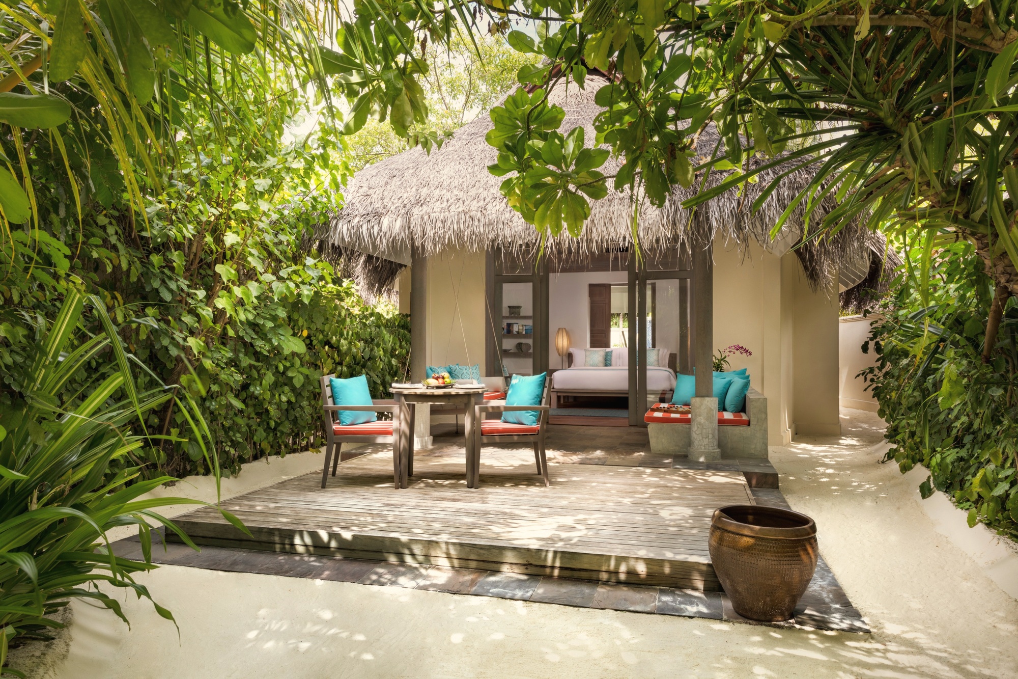 The interior of a beach pool villa, open-plan living space with direct garden and pool access.