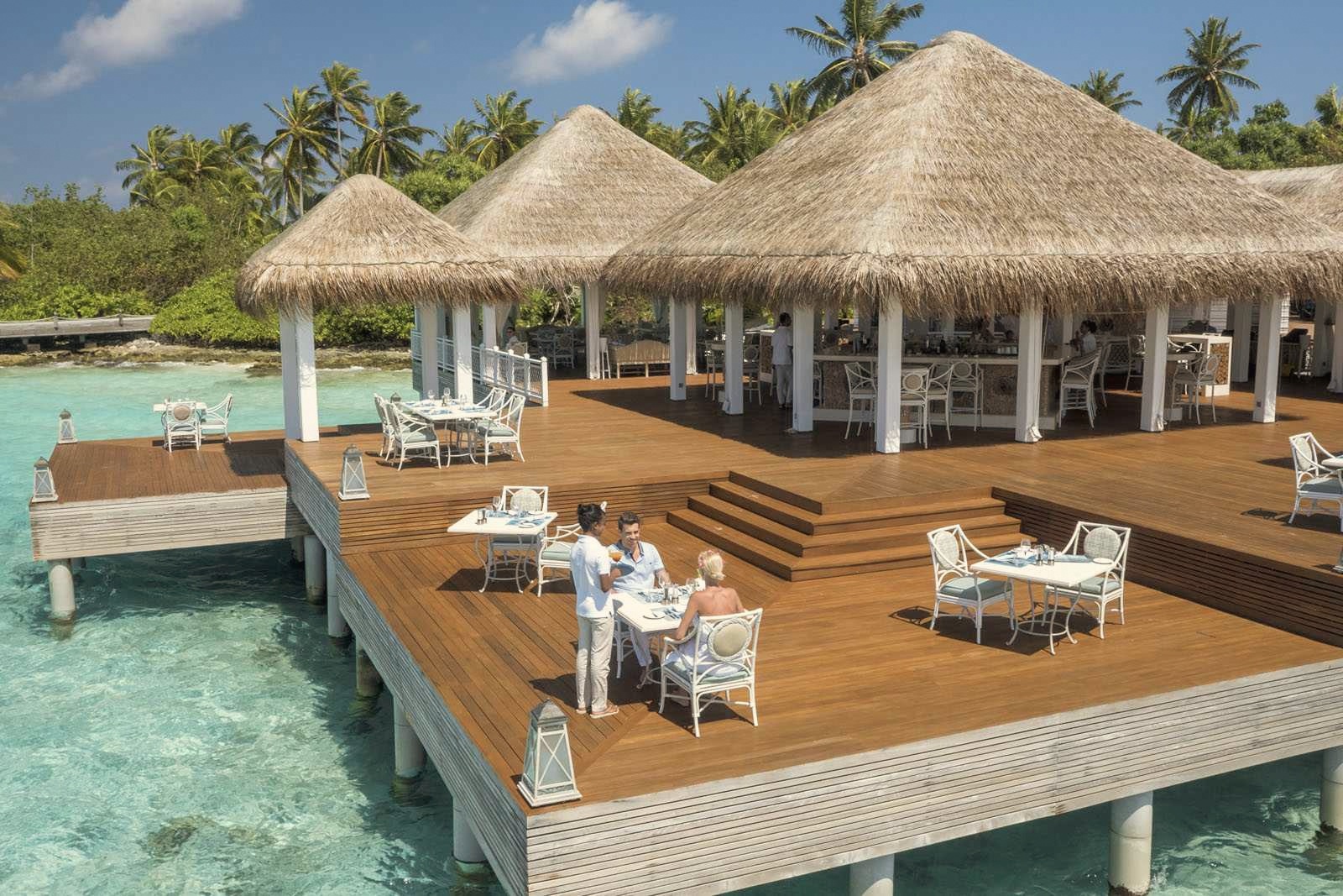 The main dining terrace at dusk. The full-service dining operation covers multiple venues across the island, with the evening meal typically taken outdoors.