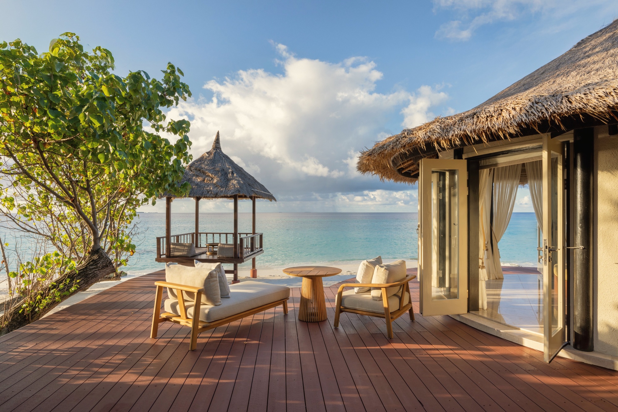 The lagoon edge from a villa deck. The water at Vabbinfaru is shallow and clear, and the transition from pool to beach to sea is the defining spatial experience of the resort.