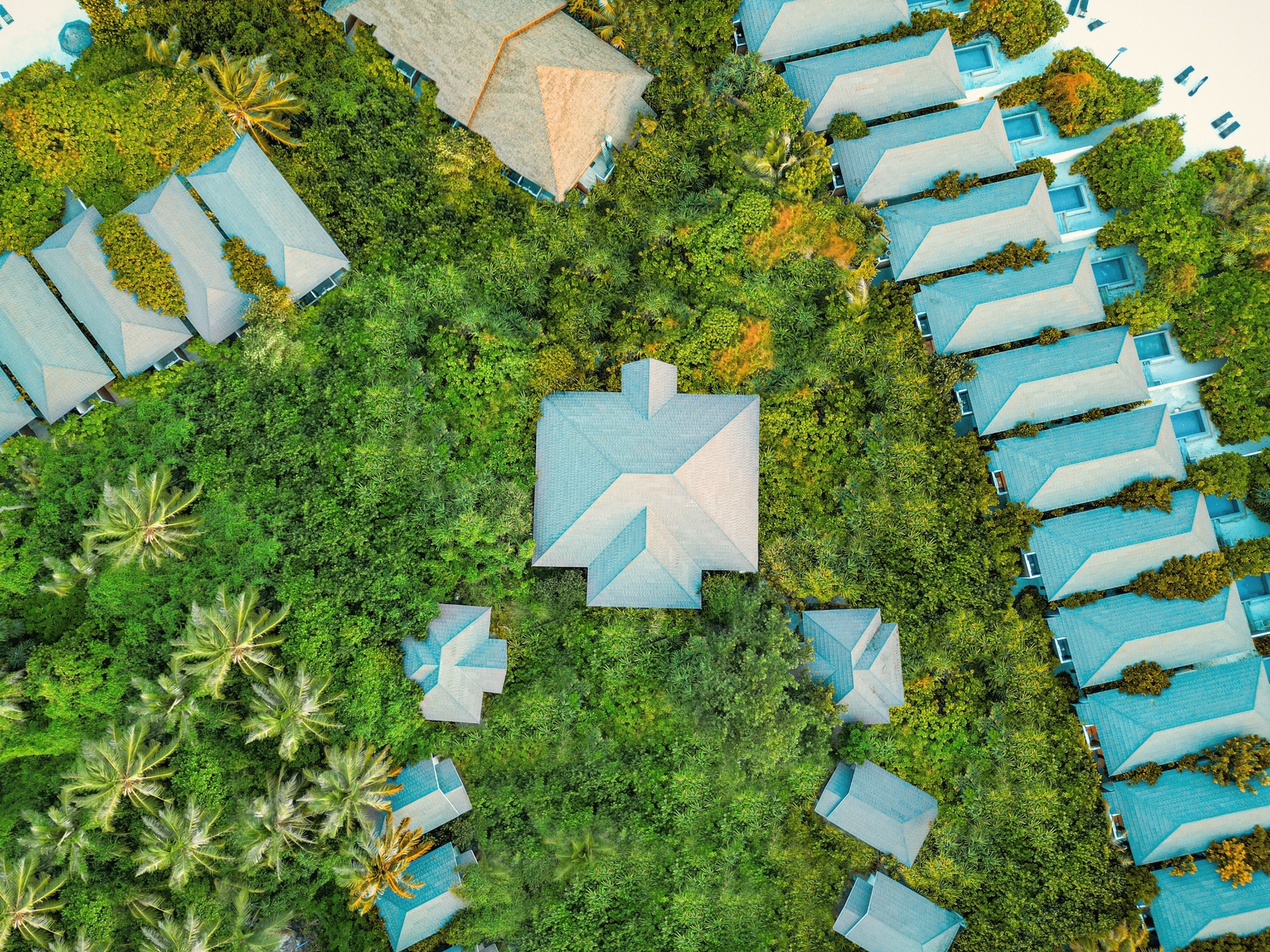 Kottefaru from above. A compact island in Raa Atoll, the overwater villa jetties extending into the lagoon on one side and the beach villas lining the sand on the other.