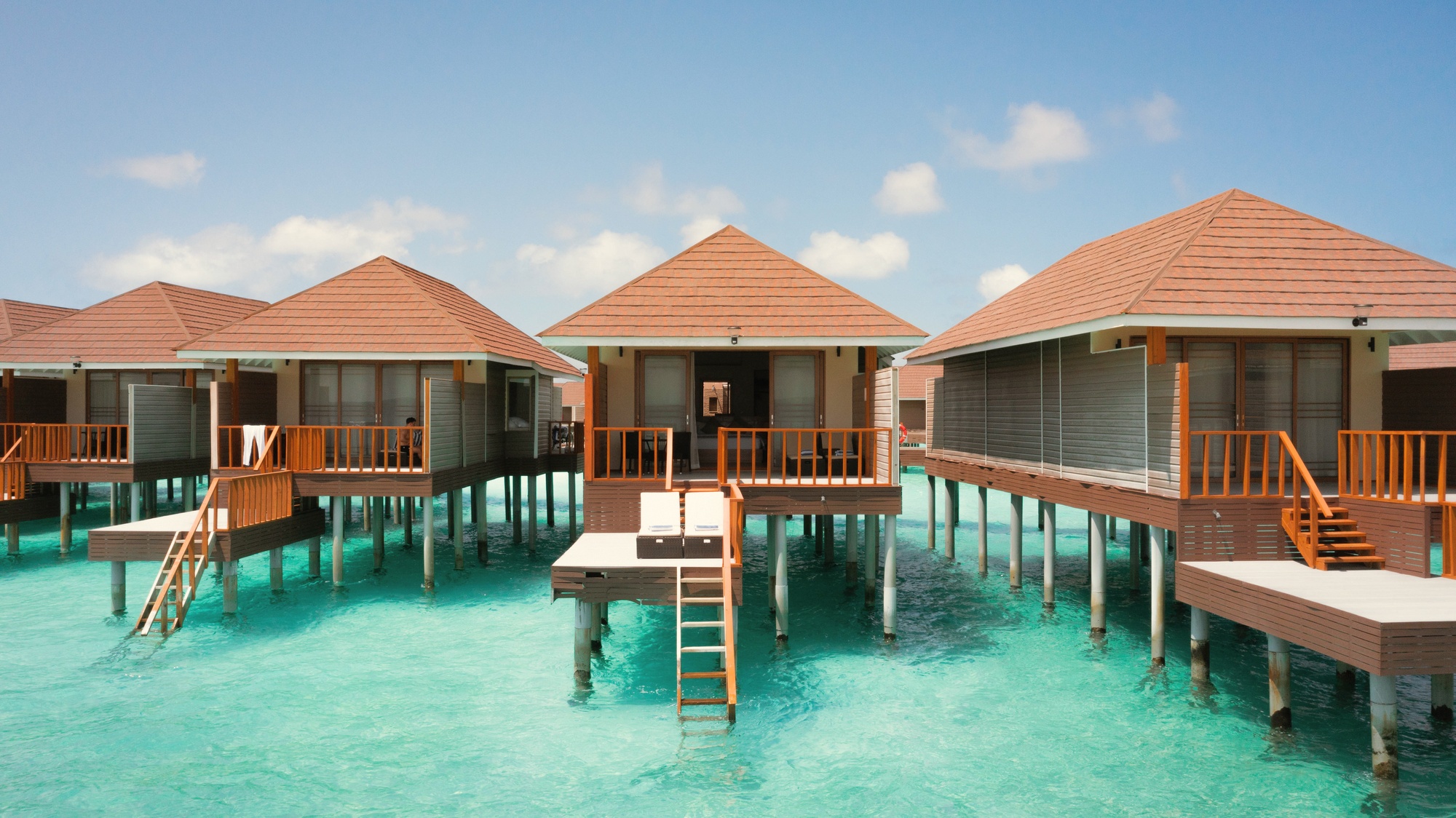 An overwater pool villa from the deck. The lagoon stretches to the reef edge with no other island visible from this position.