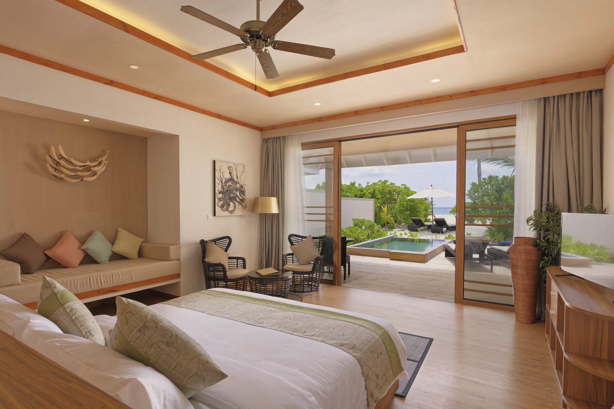 The interior of a beach pool villa. Private pool set into the garden, direct sand access beyond the boundary wall.