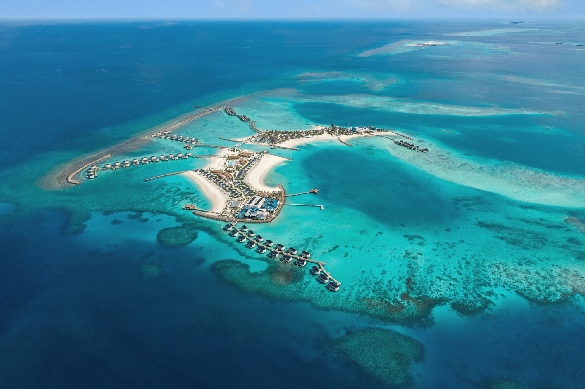 Centara Grand Lagoon from above. The resort sits within The Atollia, a two-island destination in North Malé Atoll, with overwater villas extending across the lagoon.