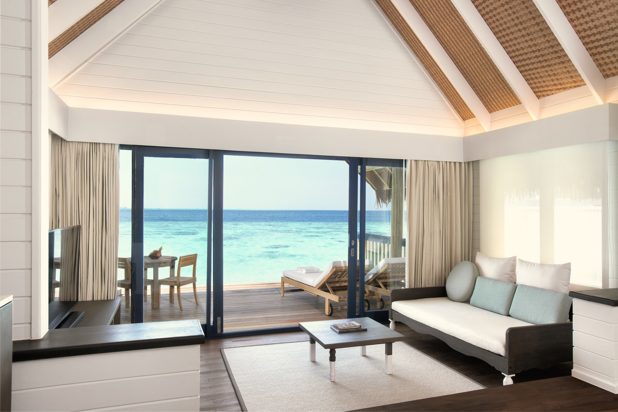 The interior of a dhoni villa looking out to the lagoon. The water is directly below the deck; the house reef begins a short swim from the steps.