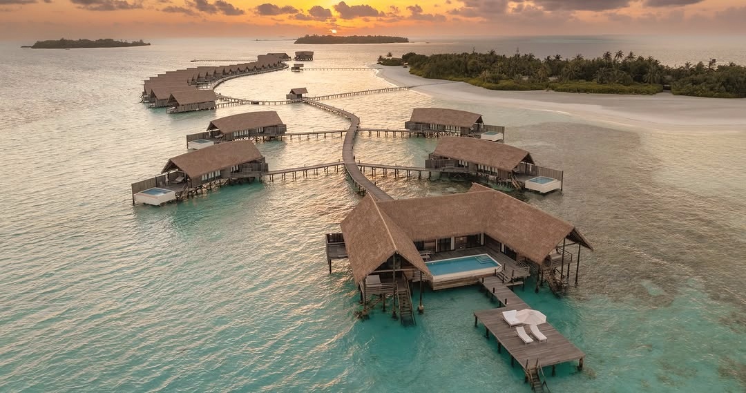 Makunufushi from above. The island sits alone in South Malé Atoll, its thirty-three overwater villas arranged along the lagoon edge in the form of traditional dhoni boats.