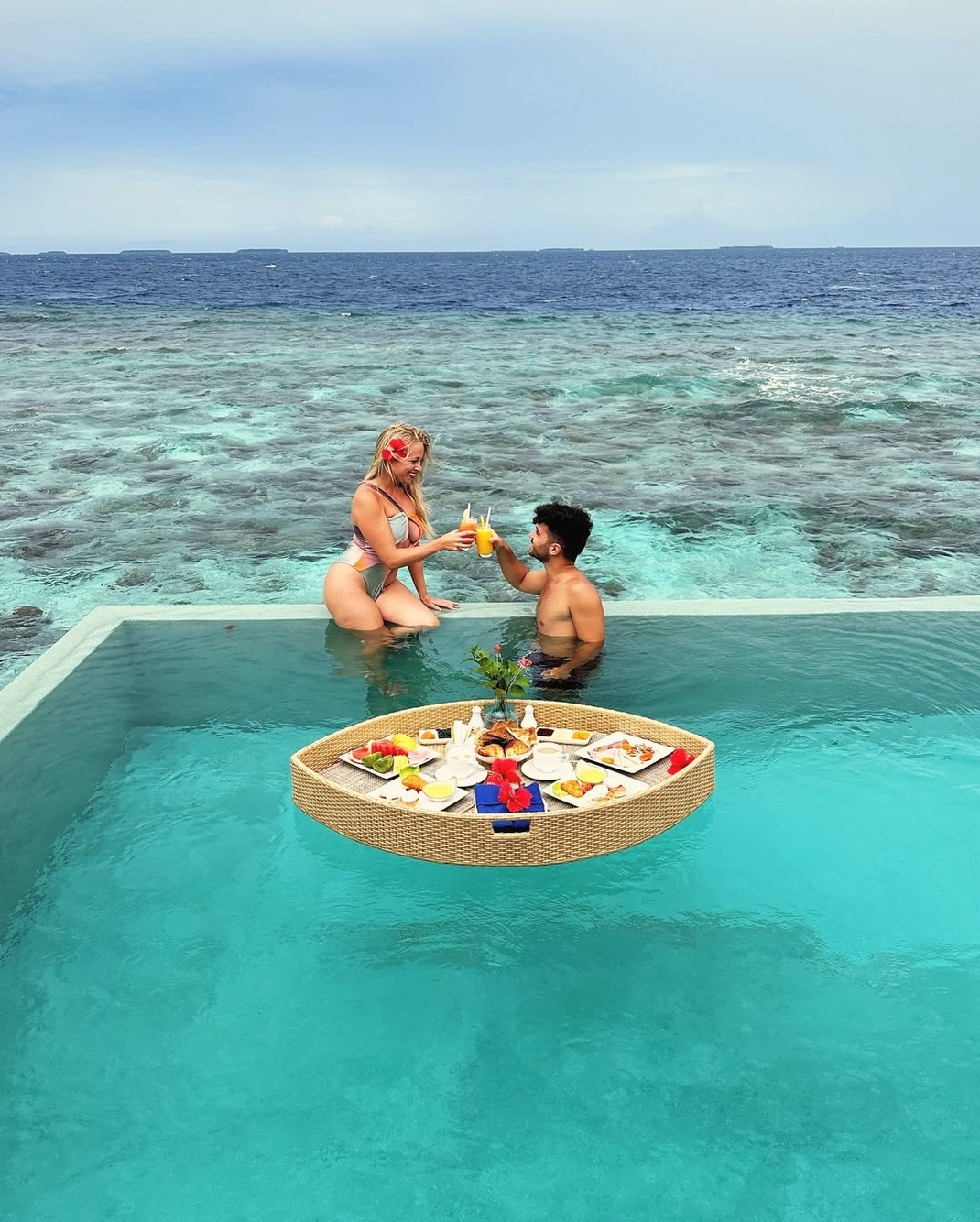 An overwater pool villa from the deck. The lagoon edge is the primary view, with the reef visible in the shallows below.
