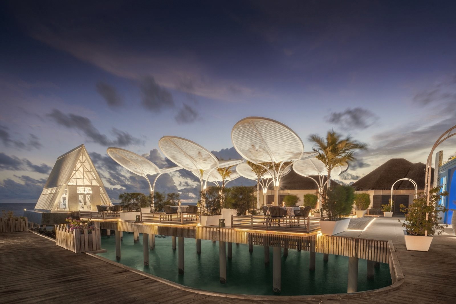 The main dining venue at Furaveri. Tables set for dinner with the lagoon as the backdrop, open to the evening air.