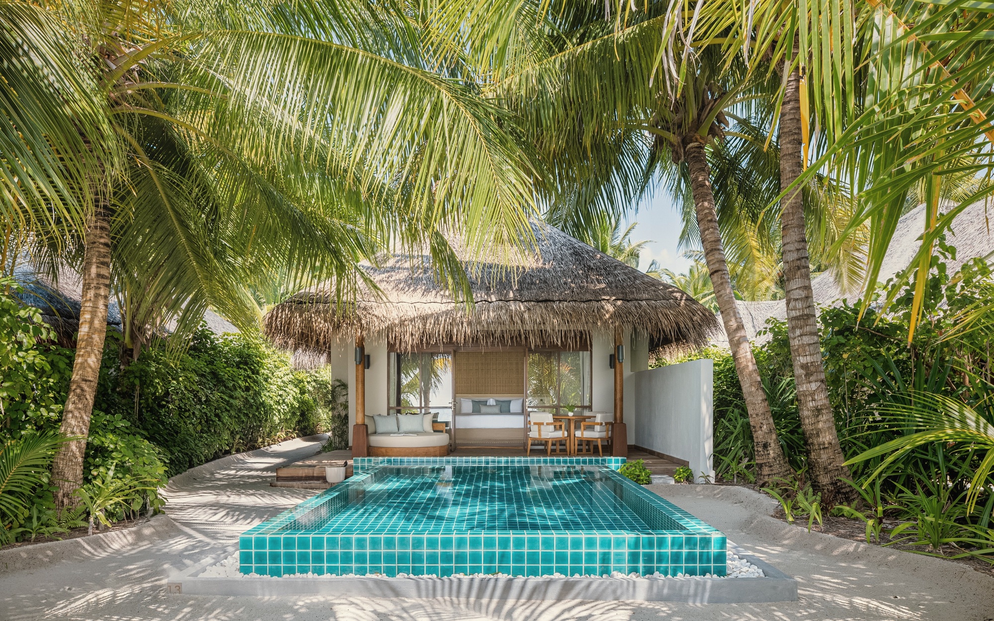 The private pool of a beach villa, set between the villa and the sand. Direct beach access beyond.