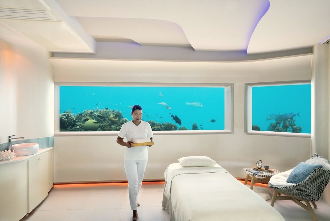 Inside the LIME spa's underwater treatment room. The lagoon surface is visible through the glass walls on all sides.