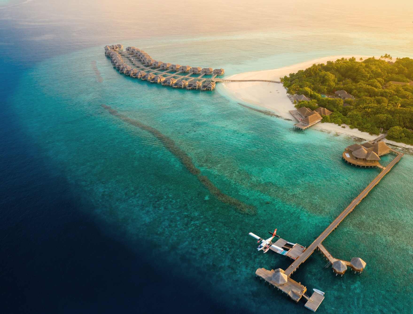The private island shoreline at low tide. The beach wraps the island and is accessible from every villa category.