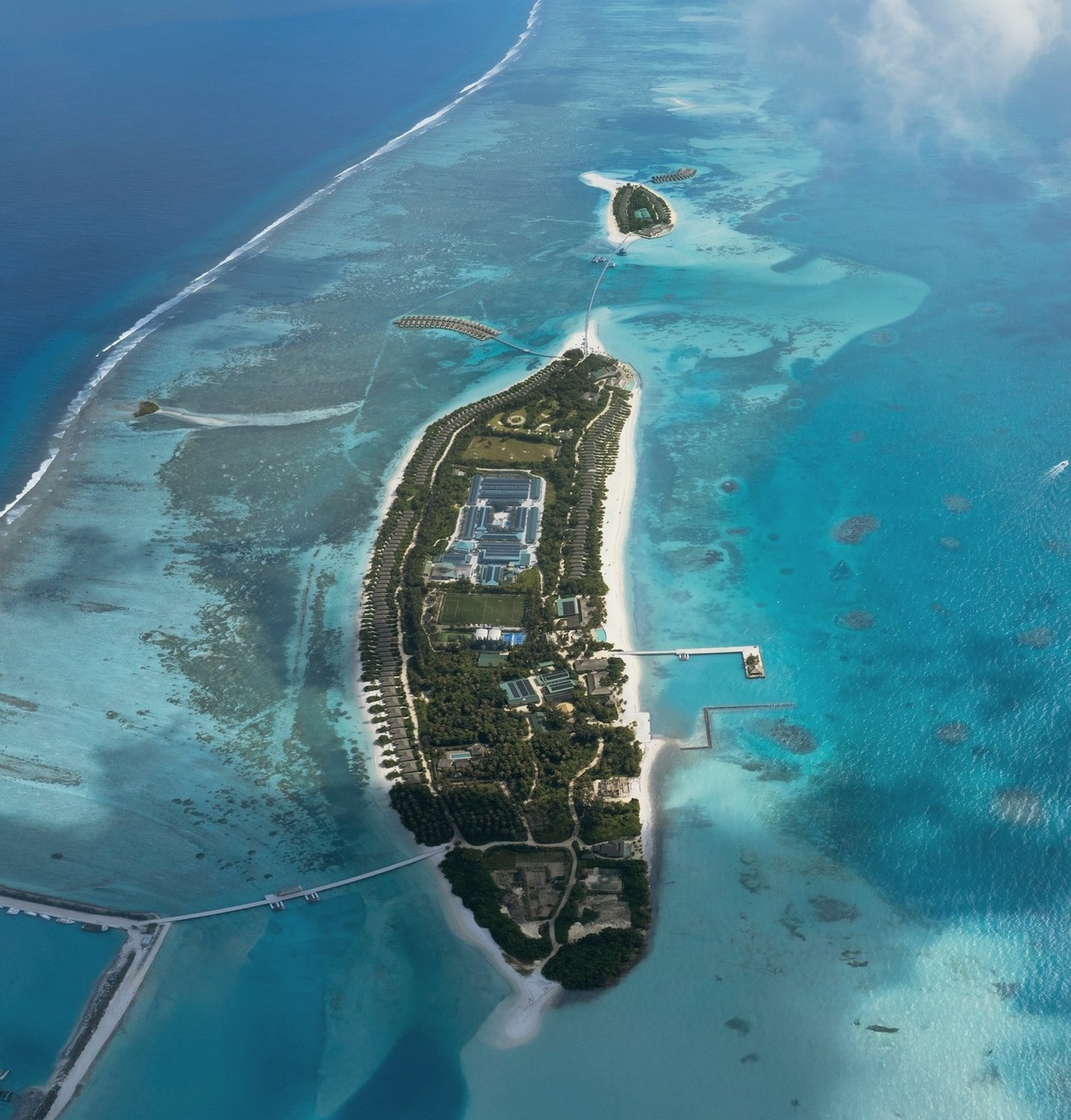 Jawakara Island from above. The resort occupies its own private island, with the lagoon wrapping the villa clusters on both the beach and overwater sides.