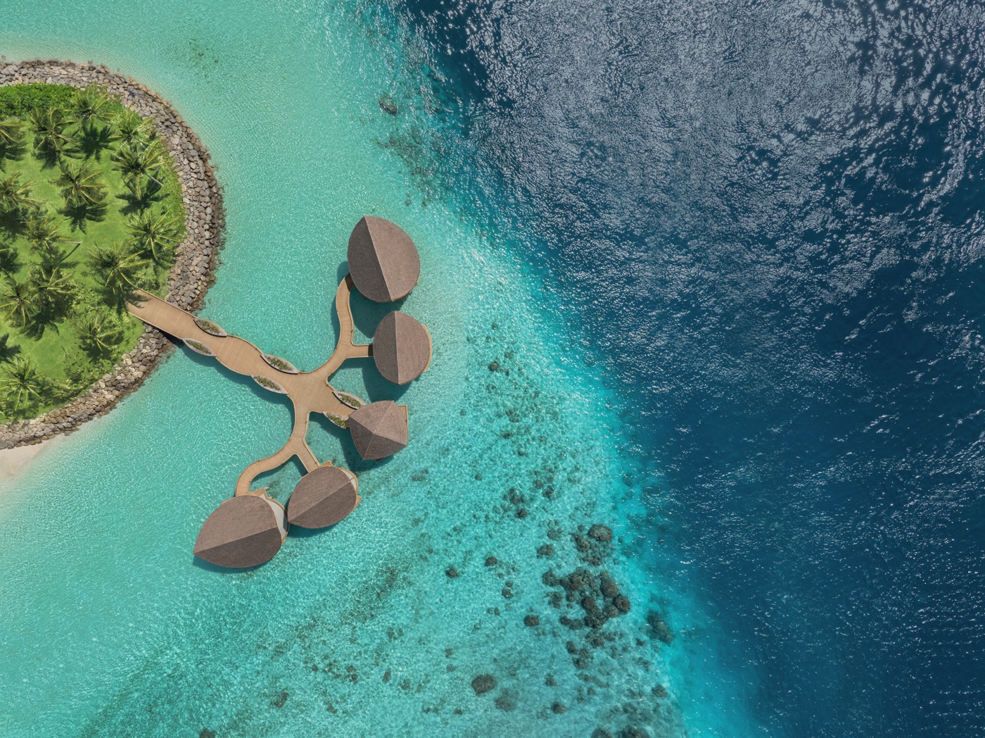 Hathaa Finolhu from above. The island sits in Kaafu Atoll, the overwater villa jetties extending into the lagoon from a densely vegetated centre.