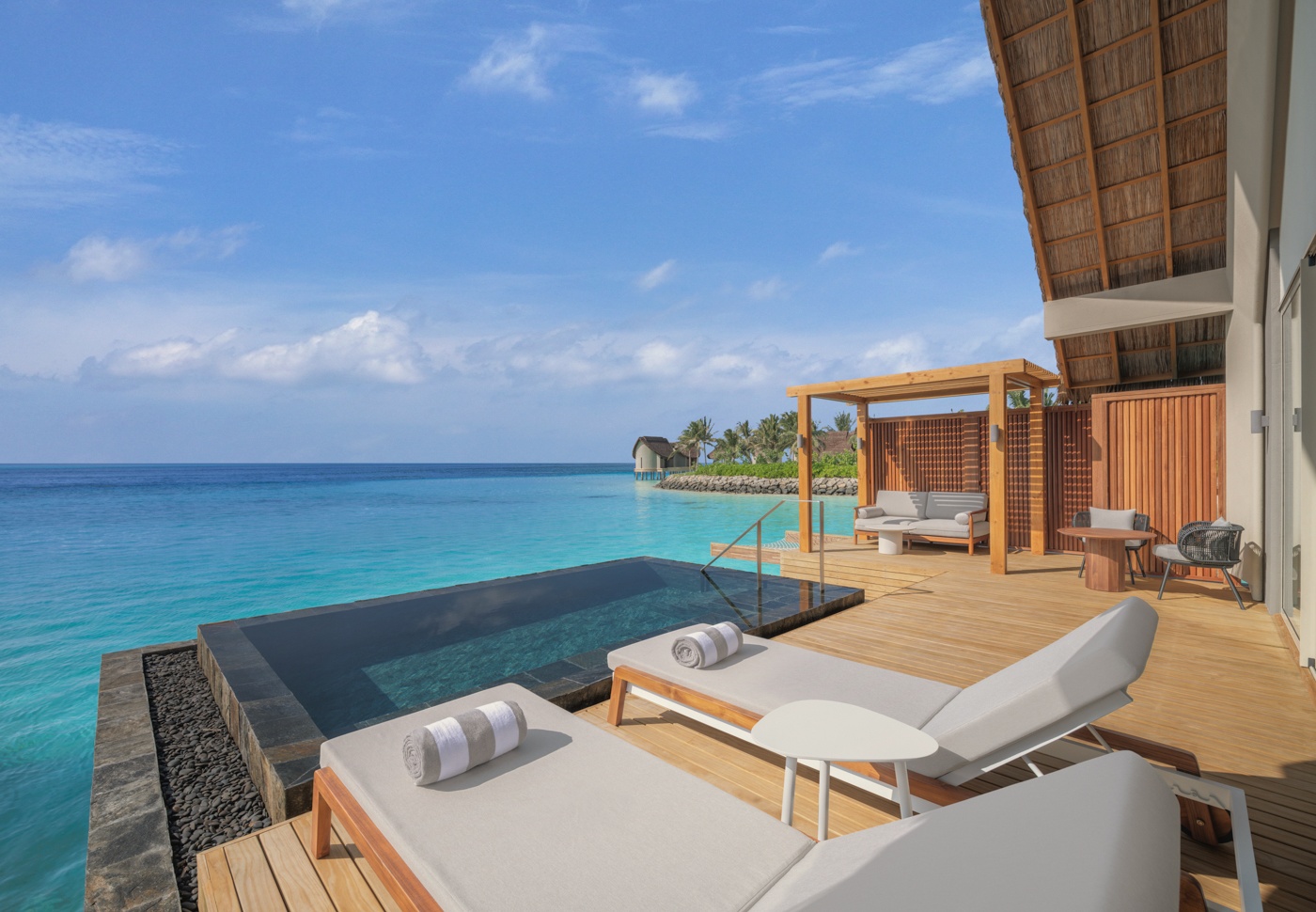 The lagoon edge from a villa deck. The water is shallow and clear, with direct entry from the private pool.