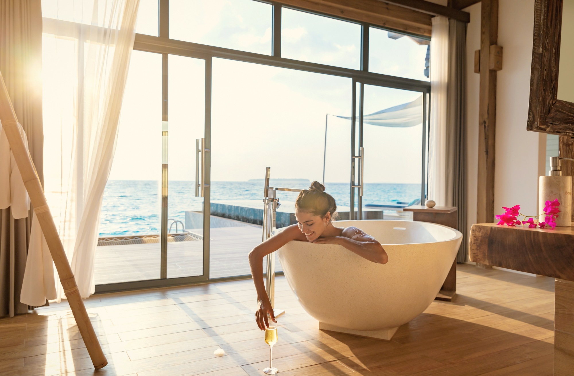 An overwater pool villa from the deck. The lagoon below is clear enough to read the coral directly from the villa.