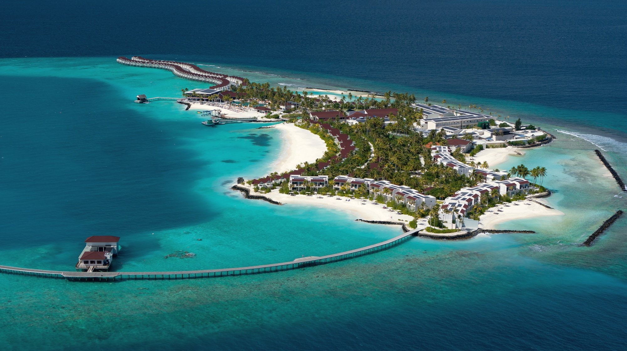 Ailafushi from above. The island sits in North Malé Atoll, the overwater villa jetties extending into the lagoon from the main island.