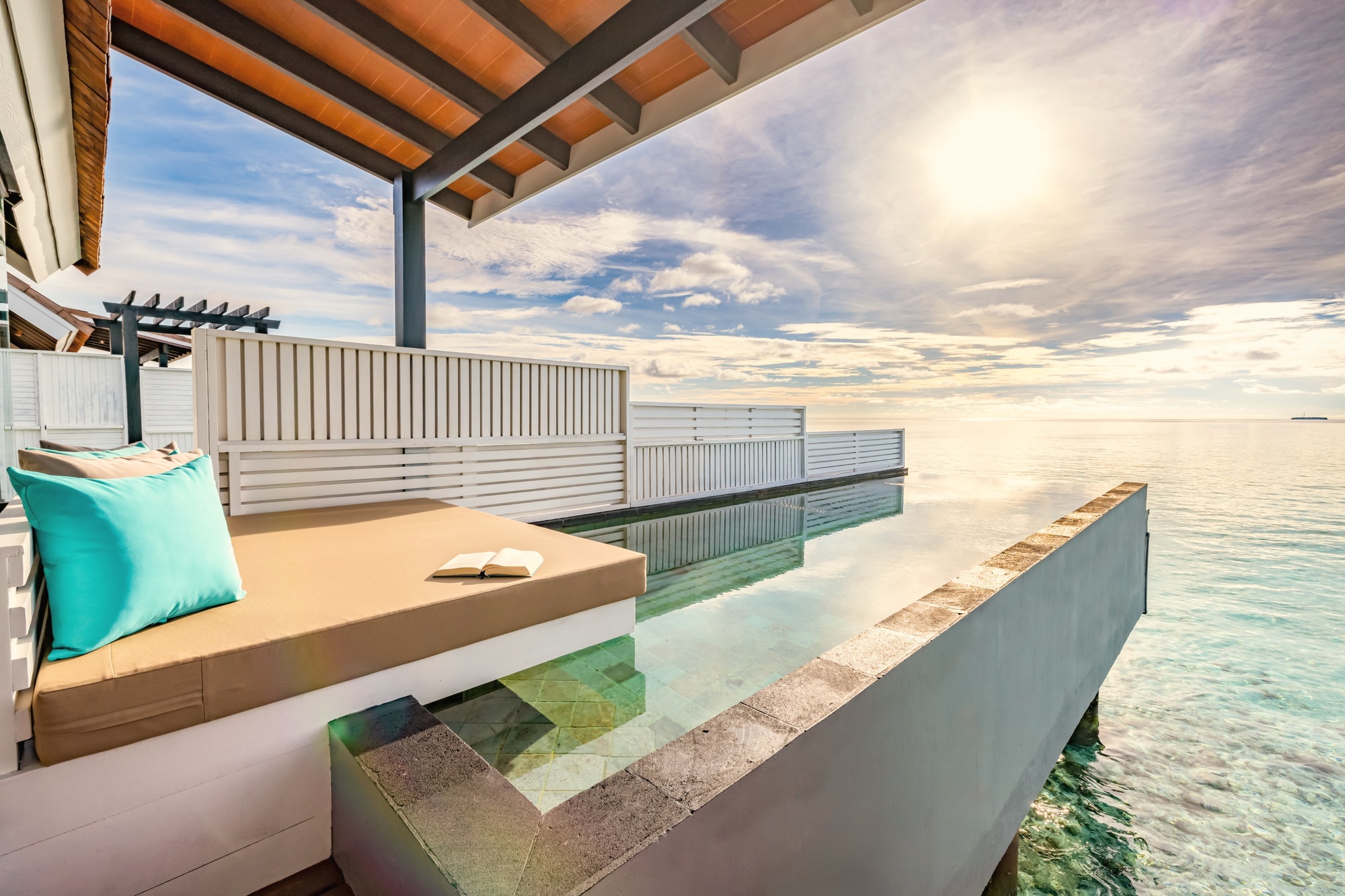An overwater pool villa from the deck. The lagoon edge is its own room, the water calm enough to enter directly from the villa platform.