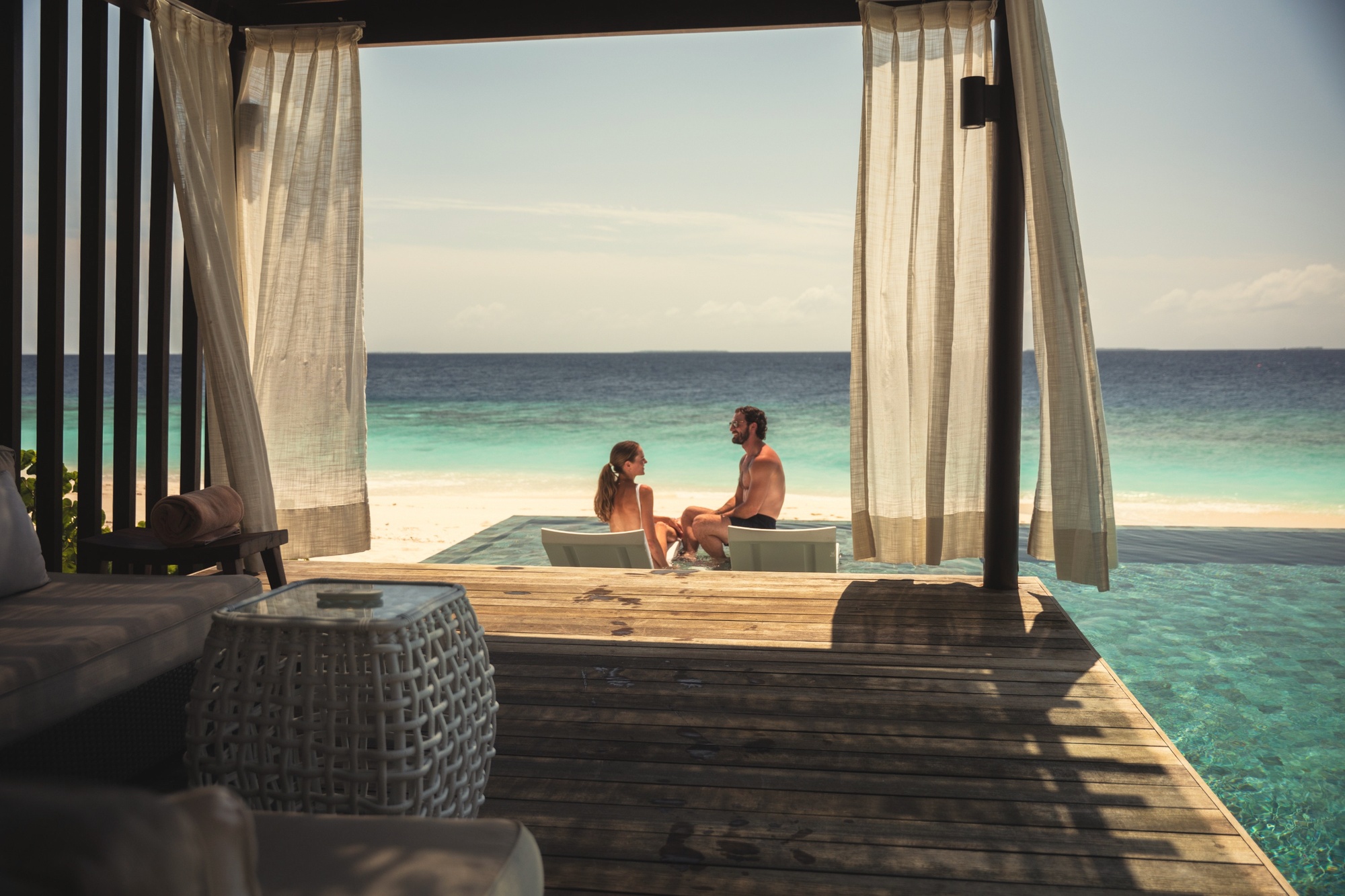 The interior of a beach pool villa. Barefoot-luxury finishes, private pool, and direct beach access in a configuration that reads as a private residence rather than a hotel room.