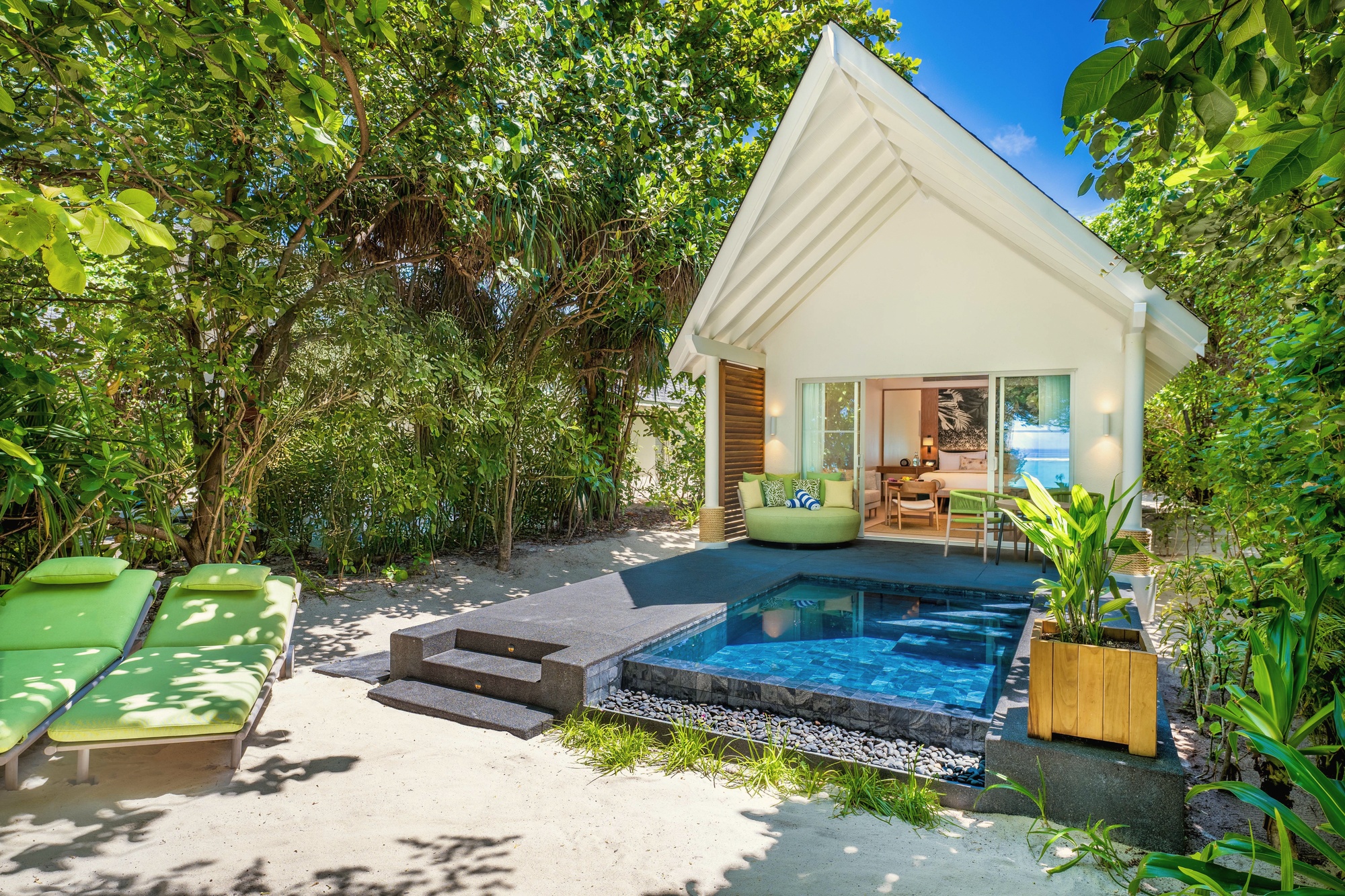 The interior of a beach pool villa. Private pool in the foreground, the Indian Ocean beyond the garden boundary.
