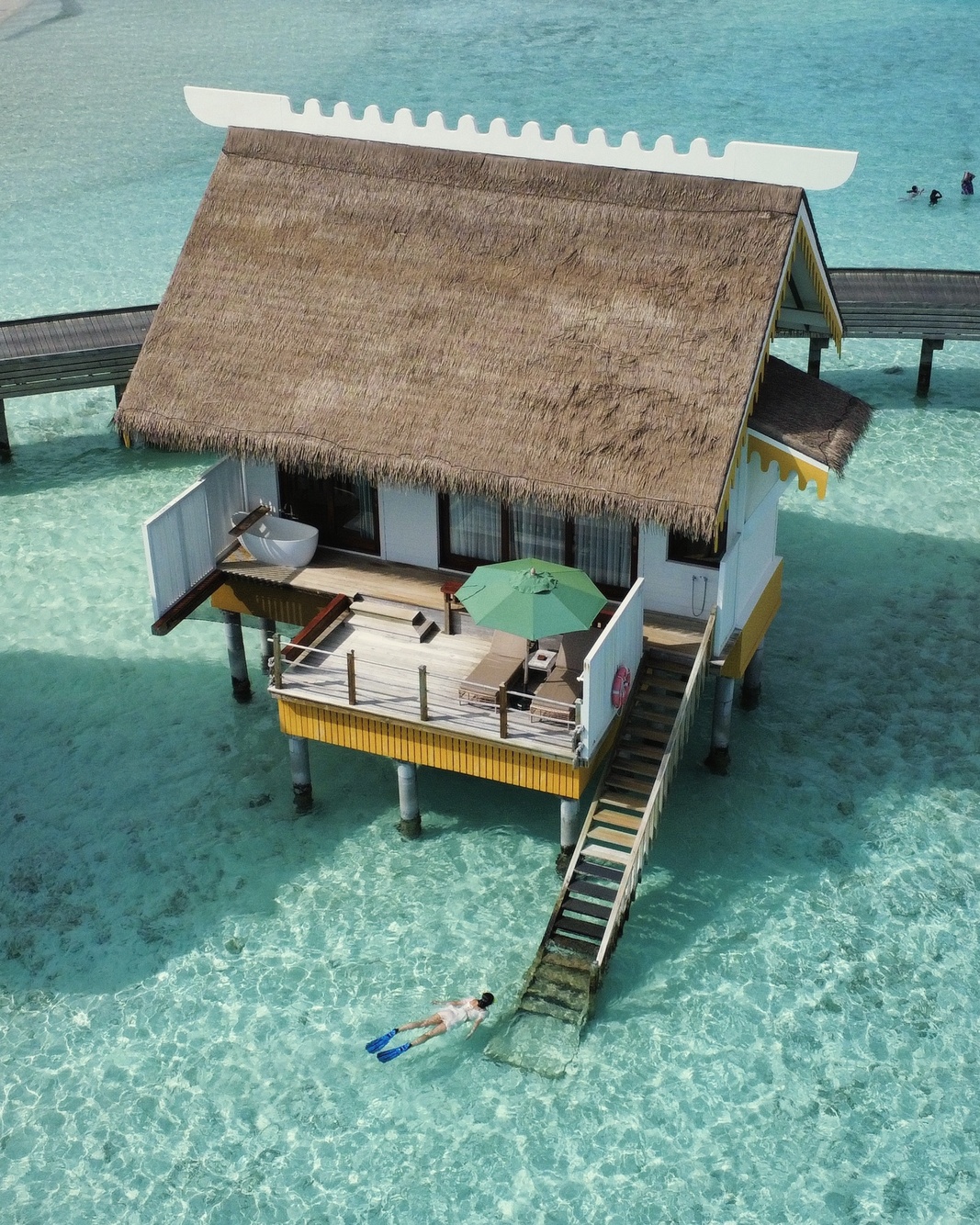 An overwater villa exterior at SAii Lagoon. The deck extends directly above the lagoon, with steps to the water below.