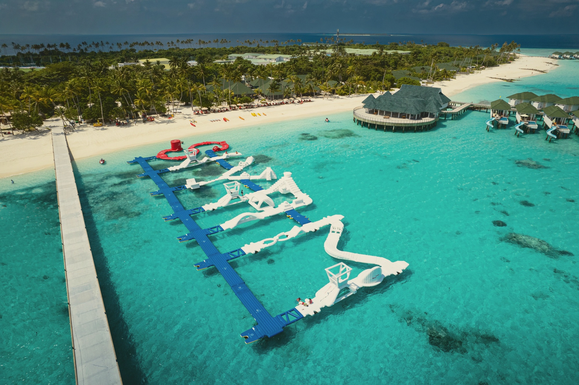 The inflatable water park from the water. The Maldives' largest inflatable course sits in the lagoon, visible from the overwater villas and accessible directly from the water.