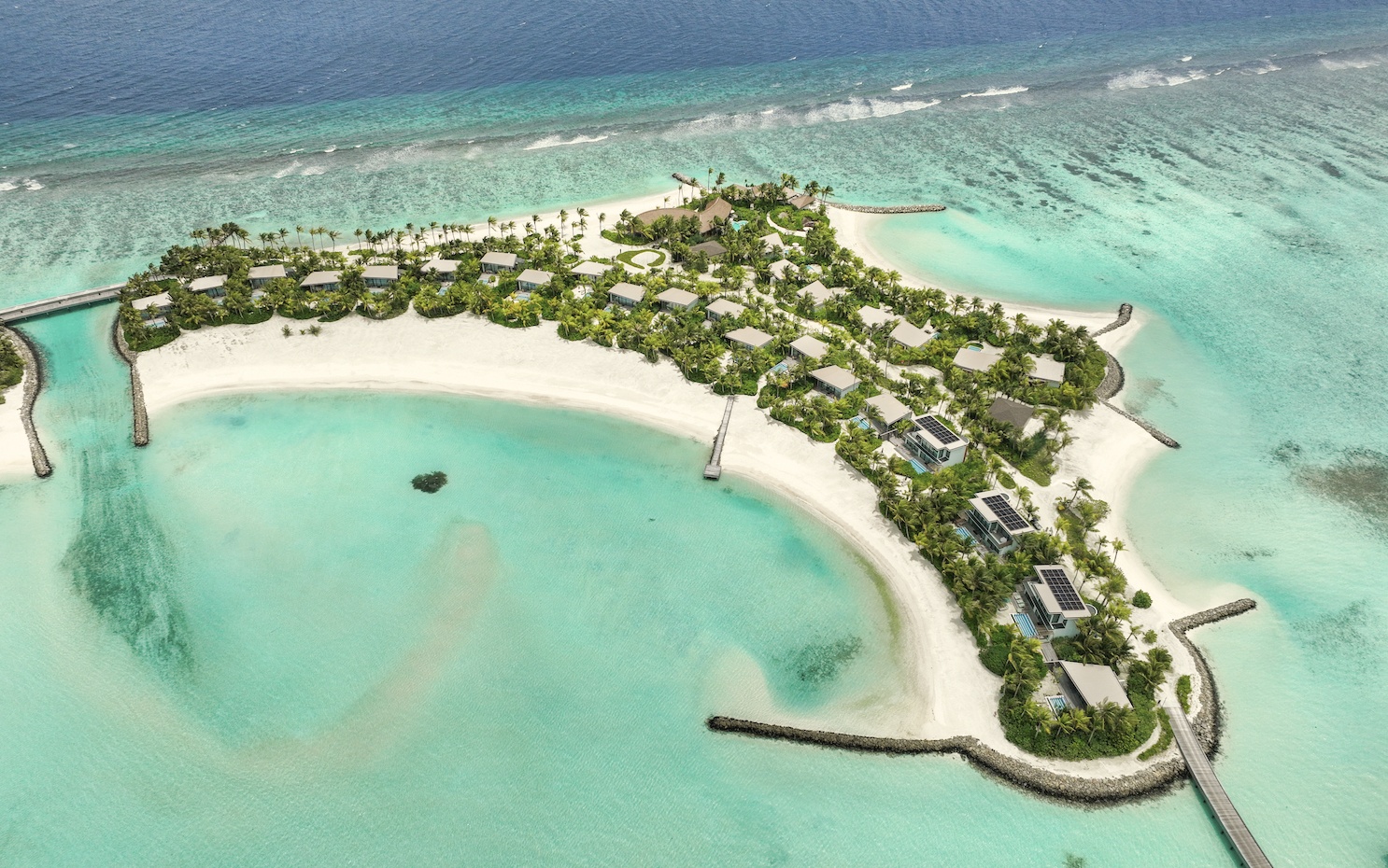 The island from above. SO/ Maldives occupies its own private island in Kaafu Atoll, the speedboat transfer visible as a white wake across the lagoon.