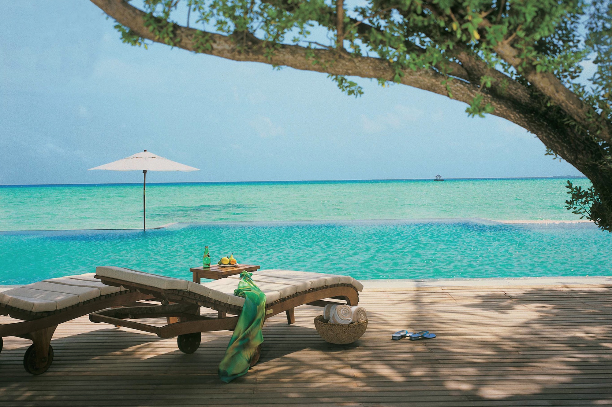 The island at low tide. The sandbank extends beyond the villa row, giving guests a private stretch of beach that is distinct from the main resort area.