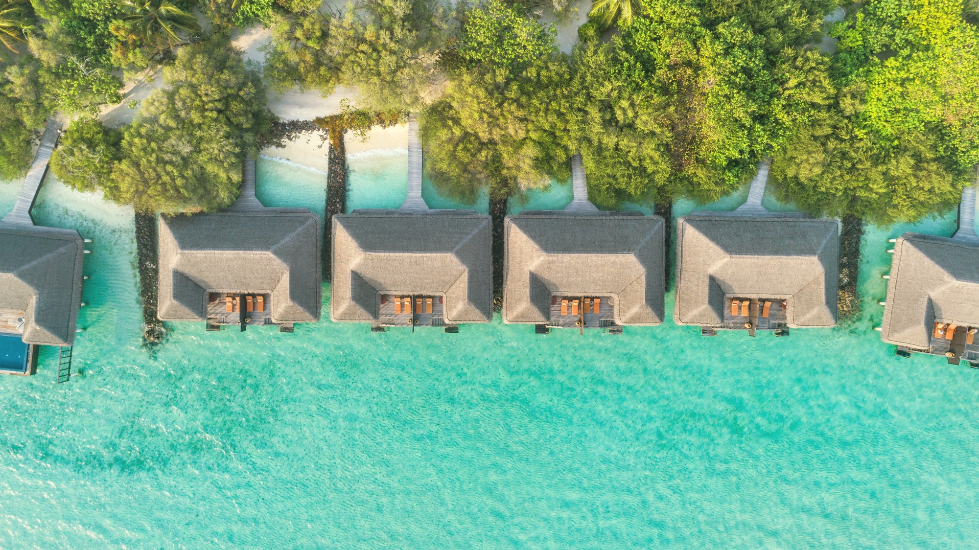 An overwater villa from the deck. The lagoon edge is the primary outdoor room, with direct water access from the villa platform.