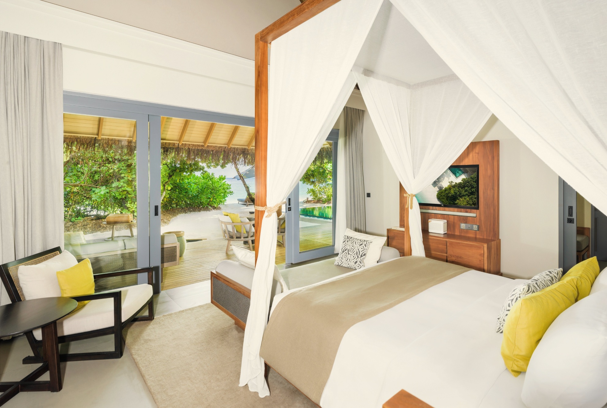 The interior of a beach pool villa. Generous proportions, natural materials, and a private pool opening directly onto the sand.