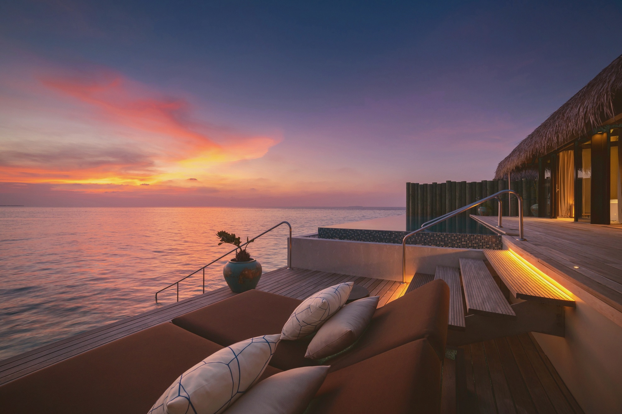 Sunset water villa deck. Velaa's overwater proposition with the orientation deliberately captured for the western light.