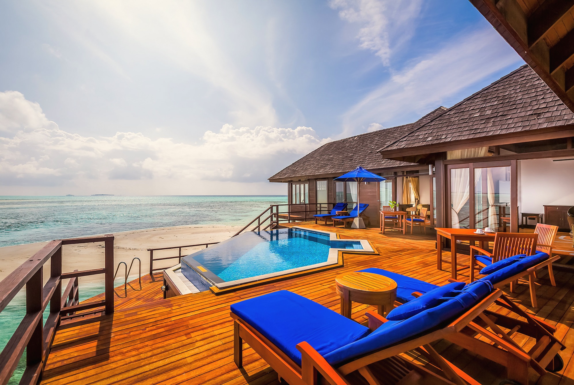 An overwater villa from the deck. The lagoon stretches out directly below, with the villa's private access point visible at the edge of the platform.